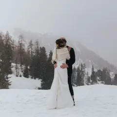 Un couple s'embrasse dans un paysage enneigé, un mariage thème montagne inoubliable.