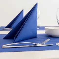 Service de table élégamment dressé avec un pliage serviette bleu vif, des couverts et des verres à vin.