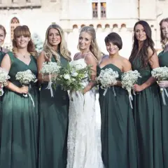 La mariée et ses demoiselles d'honneur, toutes en robes vert d'eau, tiennent des bouquets de fleurs blanches. Un mariage champêtre devant un château.