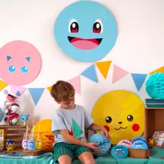 Décoration Pokémon à faire soi-même pour une fête : Pikachu, Rondoudou et Carapuce souriants, guirlandes colorées et un garçon émerveillé.