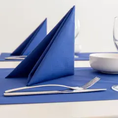 Service de table élégant avec pliage serviette cocktail bleu vif, couverts et verres à pied.