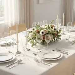 Une belle table est prête à recevoir : assiettes, verres, couverts et un centre de table floral. On sent l'envie de mettre la table pour un repas convivial.