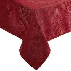 Un coin d'une table recouverte de nappes damassées rouge profond, ornées de motifs floraux complexes.