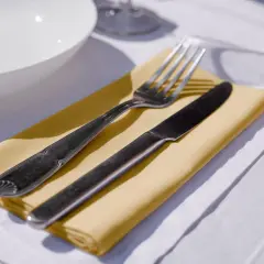 Un couteau et une fourchette reposent sur un noeud serviette de table jaune, prêt pour un repas.
