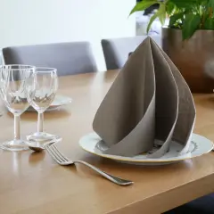 Un pliage serviette papier 2 couleurs, élégant, sur une table dressée avec des verres et des couverts.