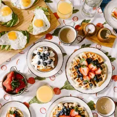 Un délicieux **heure du brunch dimanche** avec des gaufres aux fruits, des toasts à l'avocat et aux œufs, des fraises et du jus d'orange.