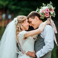Un couple s'embrasse tendrement, le bouquet de la mariée rappelant une fête foraine. Un mariage plein de joie et d'amour.