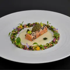 Un délicat pavé de saumon enrobé de sésame, surmonté de caviar, baignant dans une sauce onctueuse. Un plat qui pourrait faire partie d'un repas 7 services, orné de fleurs et de légumes croquants.