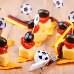 Décoration foot à faire soi même : brochettes de fromage, tomates et olives sur chips, ornées de mini ballons et de rubans aux couleurs allemandes.