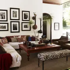 Salon avec un canapé blanc, des fauteuils en cuir marron et une banquette zébrée. Des instruments de musique et des photos en noir et blanc sur le thème rock décorent le mur.