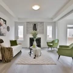 Salon moderne avec canapé blanc, fauteuils verts et une cheminée. La deco de table noir et or ajoute une touche d'élégance.
