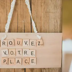 Marque place bouchon liège DIY : "Trouvez votre place" écrit avec des lettres Scrabble sur une planche en bois.