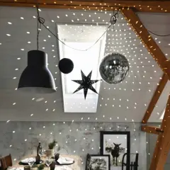 Une boule disco et une étoile décorent le plafond, projetant des lumières scintillantes. Une excellente idee deco plafond noel pour une ambiance festive.
