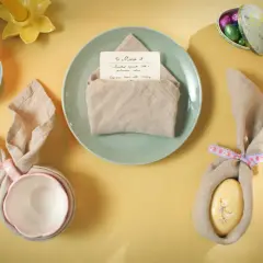 Jolie table de Pâques avec un pliage serviette bapteme en forme de lapin, des œufs décorés et des tulipes.
