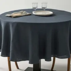 Table ronde avec nappe bleu nuit, deux chaises en bois et vaisselle. Une idée pour quel nappe choisir pour un dîner élégant.