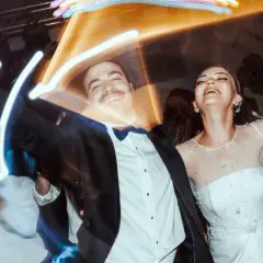 Un couple rayonnant danse joyeusement lors d'un mariage, peut-être celui d'un collègue de travail, sous des lumières festives.