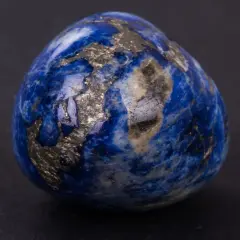 Un œuf en lapis-lazuli, rappelant les noces de saphir pour 56 ans de mariage, scintille de reflets dorés sur fond sombre.