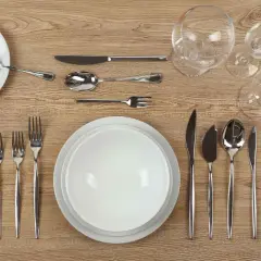 Une **fourchette sur la table** est prête pour le dîner, aux côtés d'assiettes, de verres et d'autres couverts.