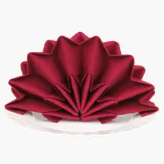 Pliage serviette tissu noël en forme d'étoile, rouge profond, sur une assiette blanche. Une touche festive pour votre table.