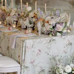 Magnifique table dressée pour un mariage de froment, avec des fleurs pastel, des bougies et une nappe à motifs floraux.