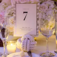 Décoration de table pour un mariage thème marin : numéro de table 7, nœud marin, bougie et verres bleus.
