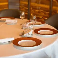 Une table dressée avec élégance, prête pour un repas. Chaque couvert est un pictogramme mettre la table, avec assiettes, verres et serviettes.