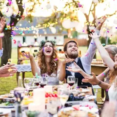 Joyeuse animation anniversaire de mariage en plein air, avec des confettis colorés pleuvant sur des invités souriants et un couple rayonnant.