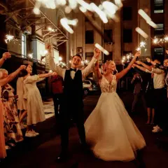 Un couple de mariés rayonnant, entouré d'invités tenant des feux de Bengale, pour un thème mariage étoile scintillant.