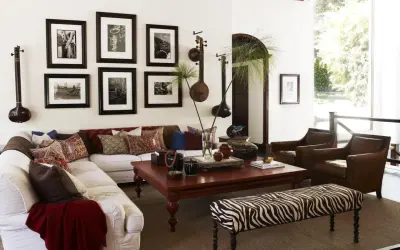 Salon avec un canapé blanc, des fauteuils en cuir marron et une banquette zébrée. Des instruments de musique et des photos en noir et blanc sur le thème rock décorent le mur.