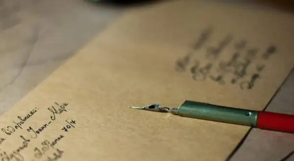 Plume et encre sur papier kraft. On peut écrire famille sur une enveloppe pour envoyer des nouvelles.