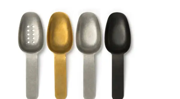 Quatre cuillères plates de différentes couleurs (argent perforé, doré, argent, noir) pour une utilisation variée.