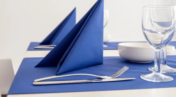 Service de table élégant avec pliage serviette cocktail bleu vif, couverts et verres à pied.