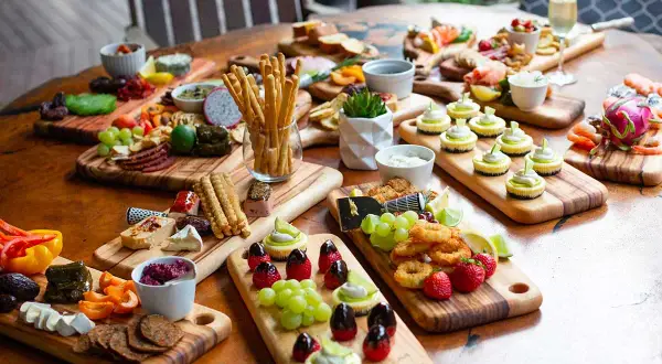 Plateaux variés pour un thème pour nouvel an : mini-cheesecakes, fruits, charcuterie, crevettes et grissini.