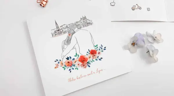 Un faire-part avec un dessin de couple devant une ville, orné de fleurs. Le texte "Notre histoire naît à Lyon..." suggère un événement spécial.