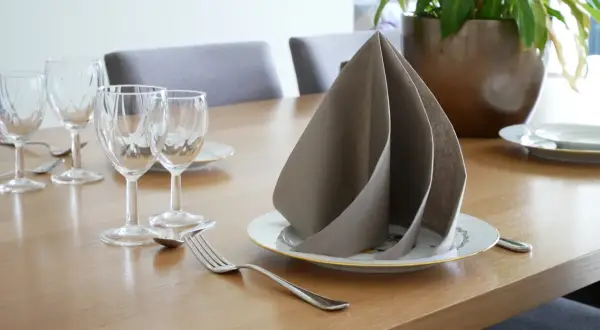 Un pliage serviette papier 2 couleurs, élégant, sur une table dressée avec des verres et des couverts.