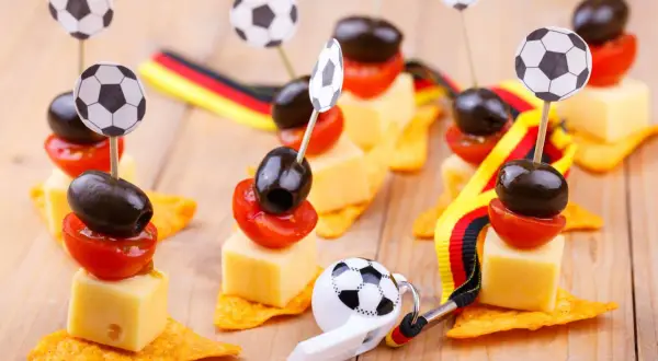 Décoration foot à faire soi même : brochettes de fromage, tomates et olives sur chips, ornées de mini ballons et de rubans aux couleurs allemandes.