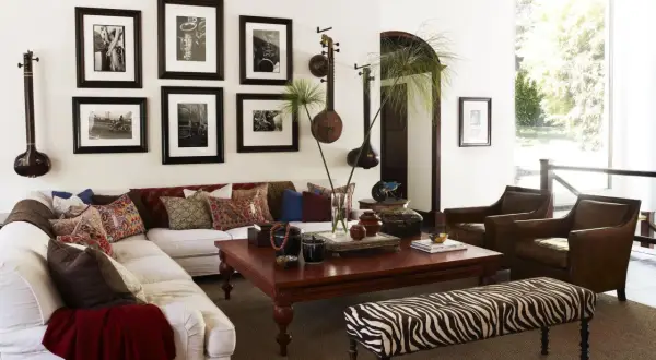 Salon avec un canapé blanc, des fauteuils en cuir marron et une banquette zébrée. Des instruments de musique et des photos en noir et blanc sur le thème rock décorent le mur.