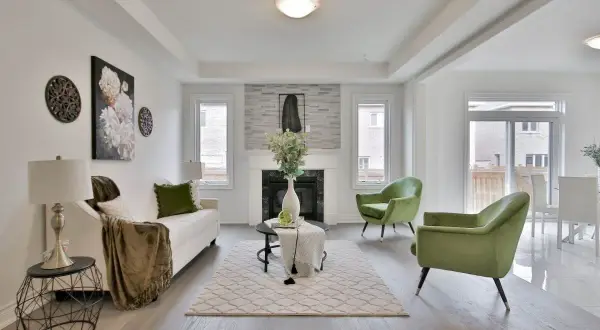 Salon moderne avec canapé blanc, fauteuils verts et une cheminée. La deco de table noir et or ajoute une touche d'élégance.