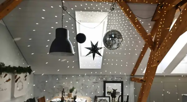 Une boule disco et une étoile décorent le plafond, projetant des lumières scintillantes. Une excellente idee deco plafond noel pour une ambiance festive.