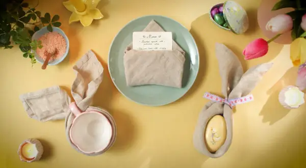 Jolie table de Pâques avec un pliage serviette bapteme en forme de lapin, des œufs décorés et des tulipes.