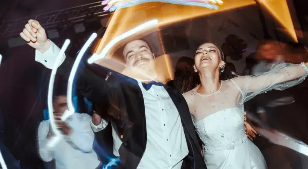 Un couple rayonnant danse joyeusement lors d'un mariage, peut-être celui d'un collègue de travail, sous des lumières festives.