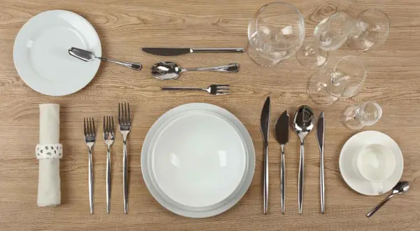 Une **fourchette sur la table** est prête pour le dîner, aux côtés d'assiettes, de verres et d'autres couverts.