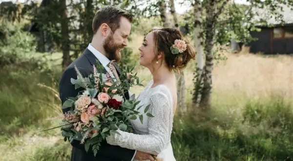 Un couple souriant, bouquet de mariage classique à la main. Idéal pour un texte remerciement mariage classique.