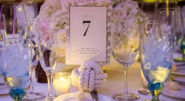 Décoration de table pour un mariage thème marin : numéro de table 7, nœud marin, bougie et verres bleus.