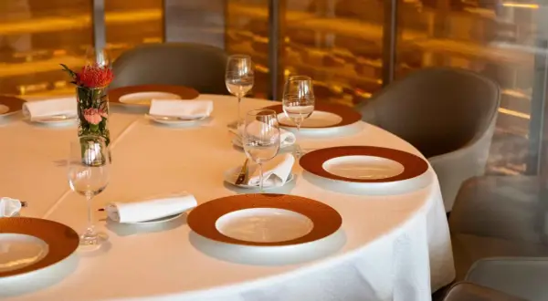 Une table dressée avec élégance, prête pour un repas. Chaque couvert est un pictogramme mettre la table, avec assiettes, verres et serviettes.