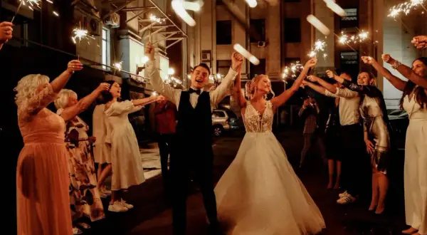 Un couple de mariés rayonnant, entouré d'invités tenant des feux de Bengale, pour un thème mariage étoile scintillant.