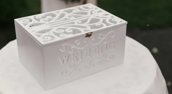 Boîte blanche décorée pour les vœux de mariage, ornée du mot "WEDDING". Une urne élégante pour recueillir les messages des invités.
