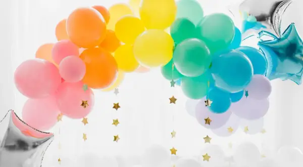 Arc-en-ciel de ballons colorés, une idée déco avec ballon à gonfler pour une fête joyeuse. Étoiles dorées suspendues.