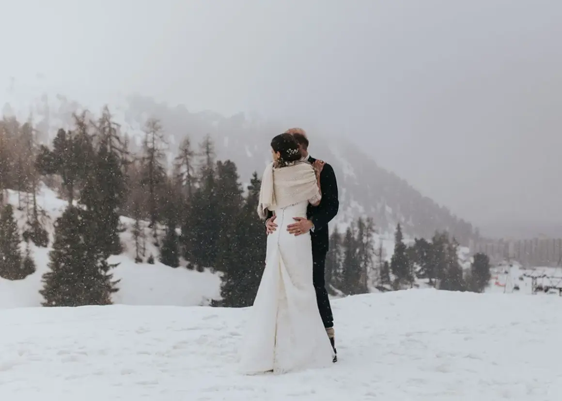 Un couple s'embrasse dans un paysage enneigé, un mariage thème montagne inoubliable.