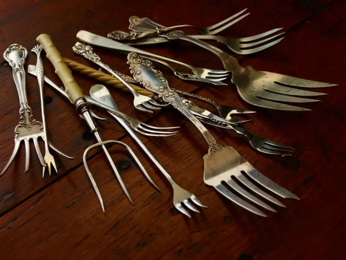 Un assortiment de fourchettes anciennes, certaines ornées, sur fond de bois. Qui a inventé la fourchette ? Ces ustensiles racontent une histoire.